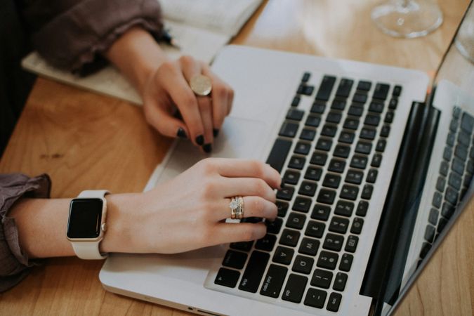 Close-up of Hands Typing on Laptop at Wooden Desk