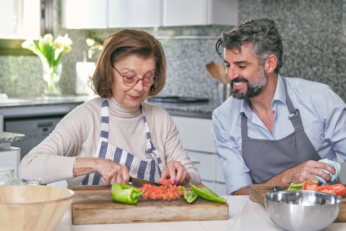 Mother cutting tomatoes near son