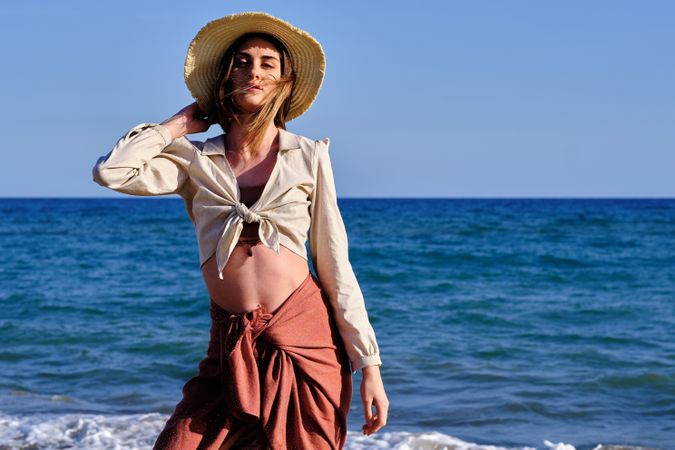 A fashion model with a hat at the beach before sunset
