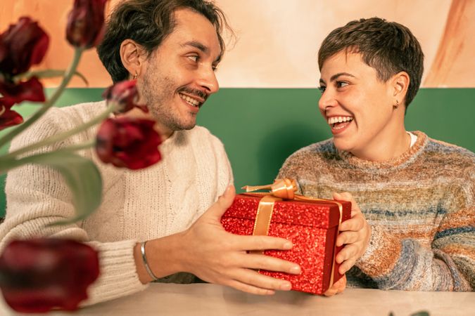 Happy diverse couple with a non-binary person sharing a gift at a celebration