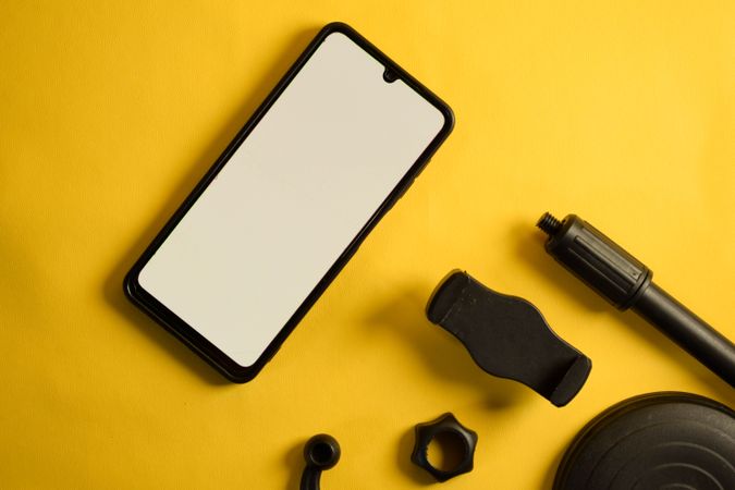 Phone and accessories on yellow background with copy space
