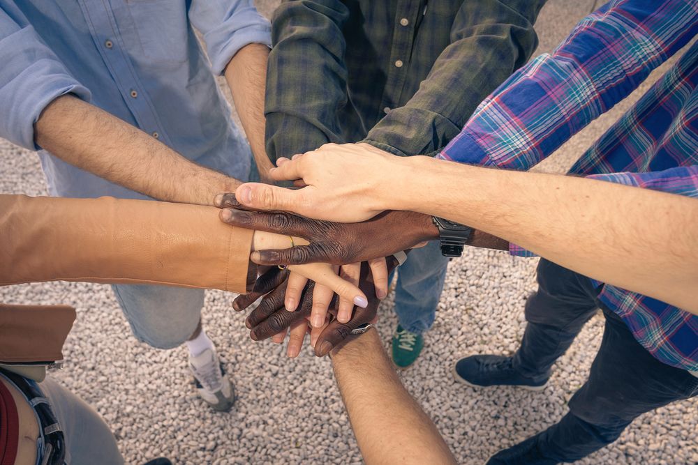 Top view of diverse people stacking their hands together in a show of unity.