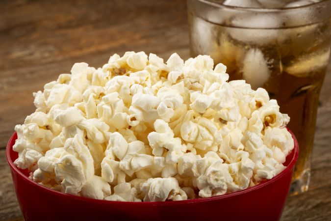 Bowl with salted popcorn and soda on the table.