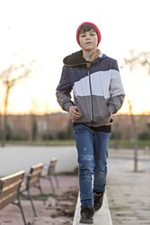 Serious teenager wearing a red hat walking in city park