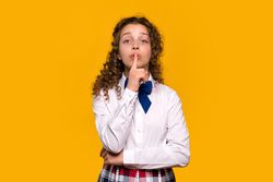 Girl making shushing gesture, finger to lips