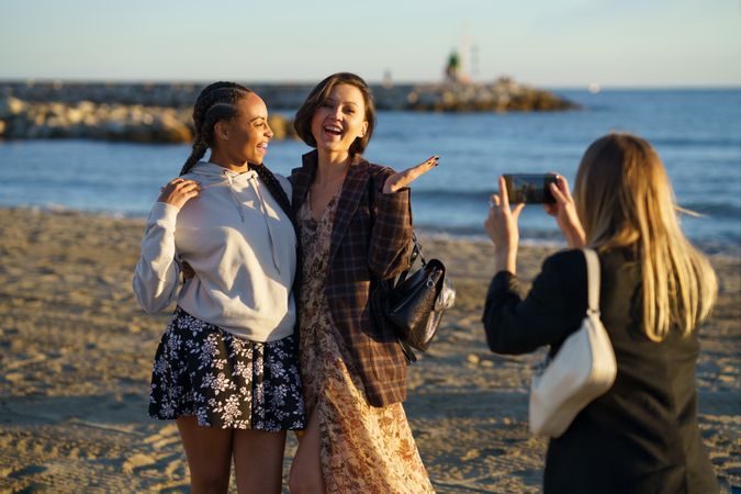 Female friends hanging out taking pictures on beach at magic hour
