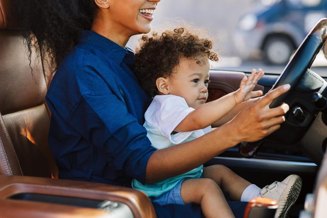 Woman sitting in car with cute little boy on lap