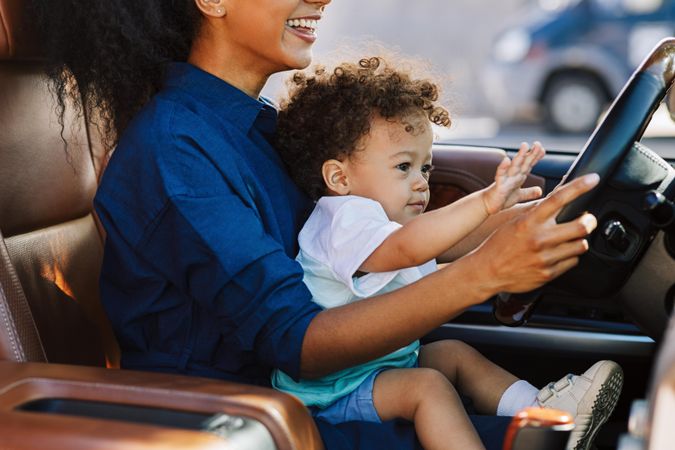 Woman sitting in car with cute little boy on lap