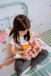 little girl playing feeding her baby doll