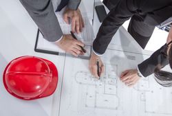 Above view of architects hands revising a house project