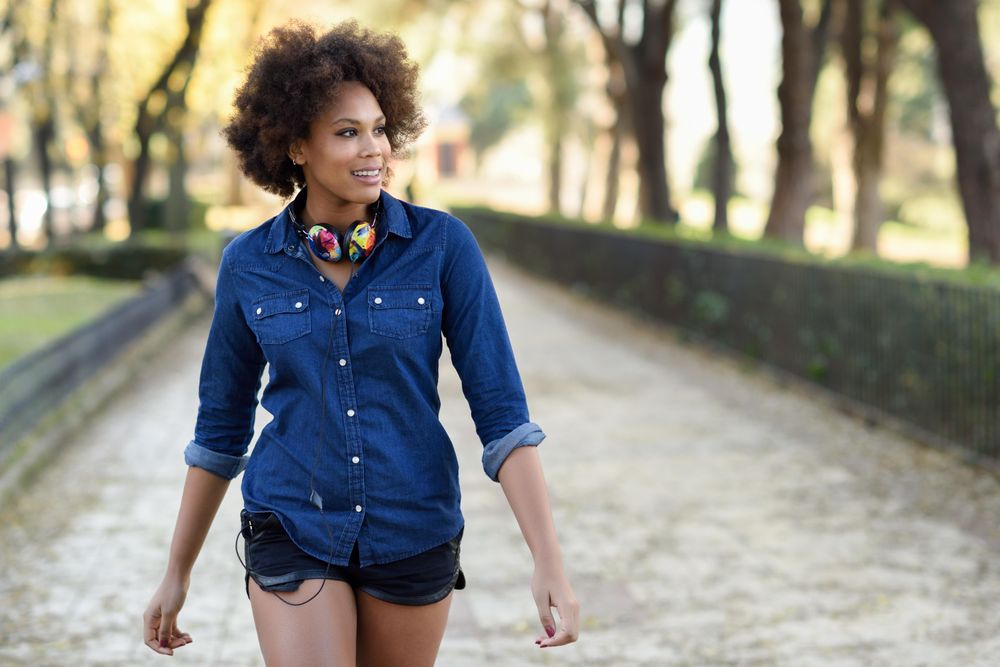 Female strolling outside in denim shirt and shorts looking to her side