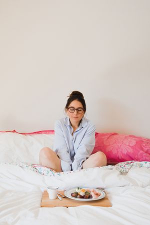 Young woman with breakfast on bed with closed eyes