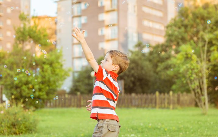 Happy boy playing with soap bubbles in the park
