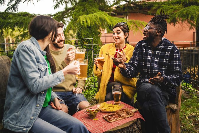 Group of multi-ethnic people drinking beers in the terrace patio having fun together
