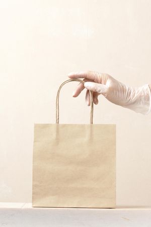 Gloved hand holding paper bag for covid protection