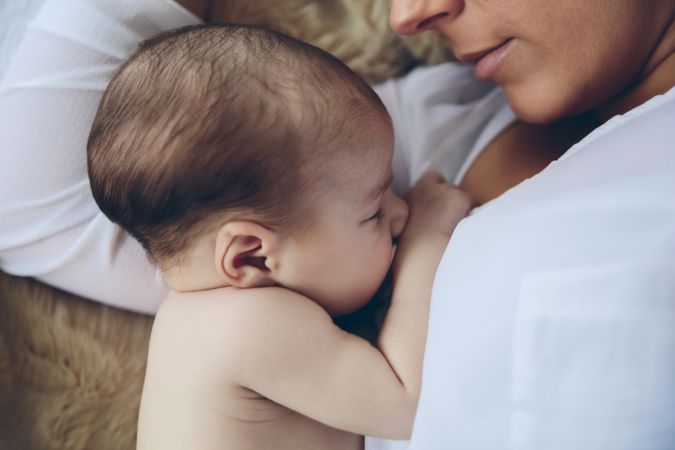 Newborn lying on the bed embraced by her mother