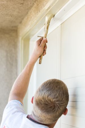 Professional Painter Cutting In With Brush to Paint Garage Door Frame