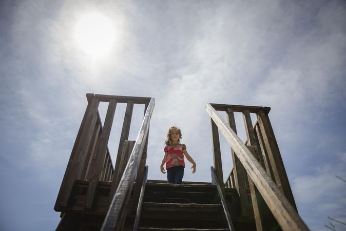 Child looking down from observation tower on sunny day