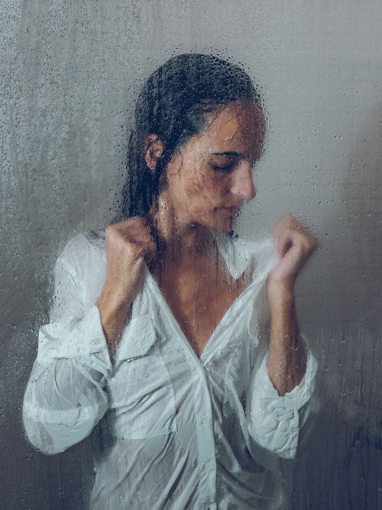 Sensitive woman in glass shower cabin