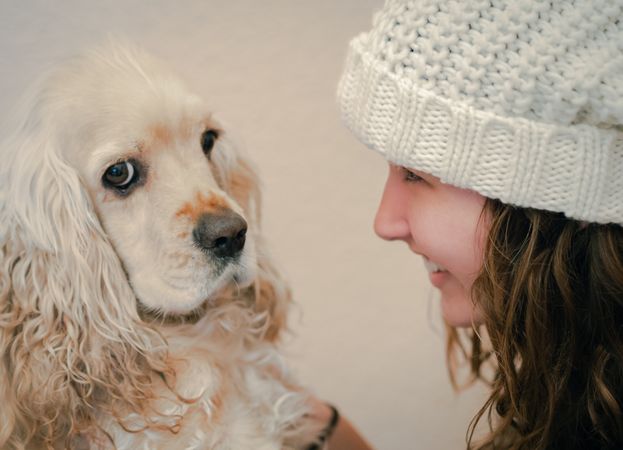 Teen in hat playing with dog