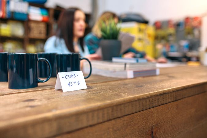 Close up of blue breakfast mugs for retail sale over wooden counter in vintage shop
