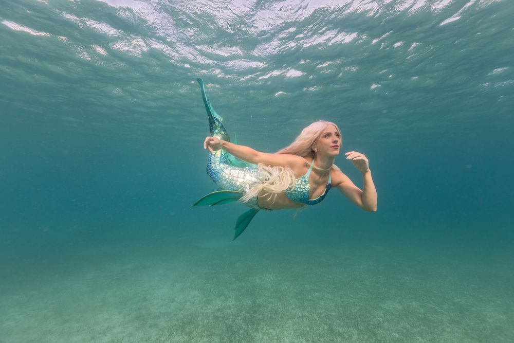Blond fairytale female mermaid swimming underwater