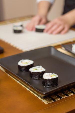 Closeup of Japanese sushi rolls with rice, avocado and shrimps on nori seaweed sheet on plate