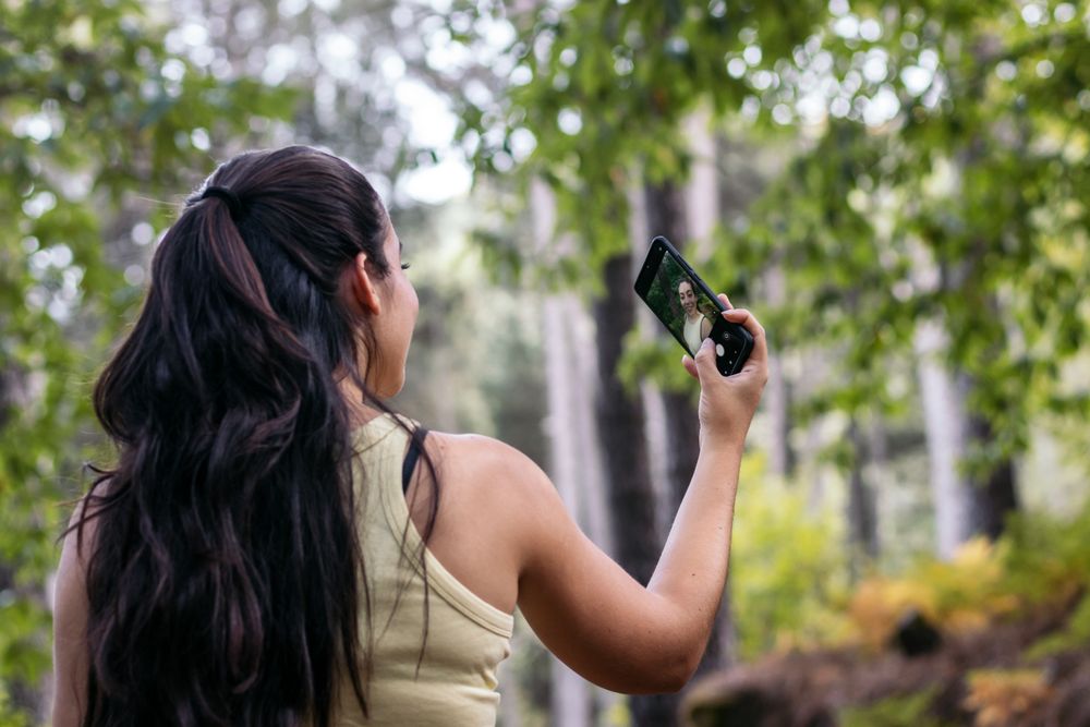 Young woman taking selfies with smartphone in the forest