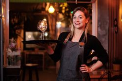 Cheerful waitress holding tray with wineglasses