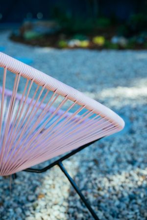 Close up of stylish pink outdoor garden chair on a rock patio
