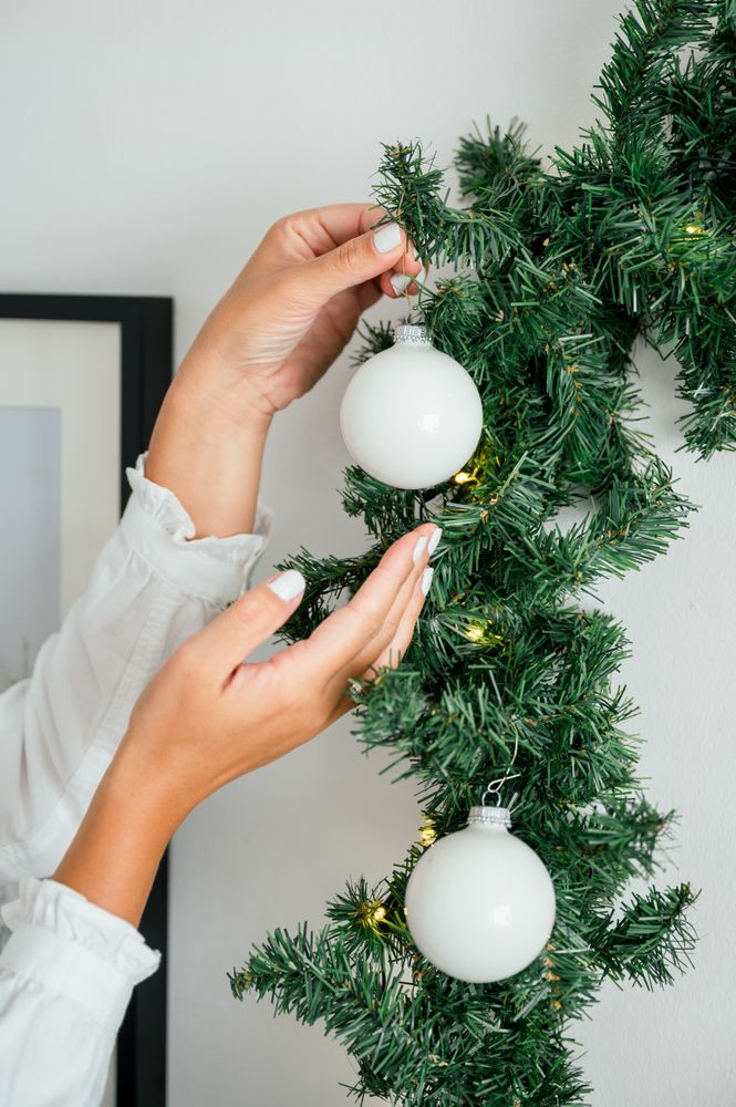 Christmas ornament being put on the Christmas tree by an unrecognizable woman