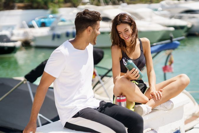 Man and woman talking together on pier with water bottles