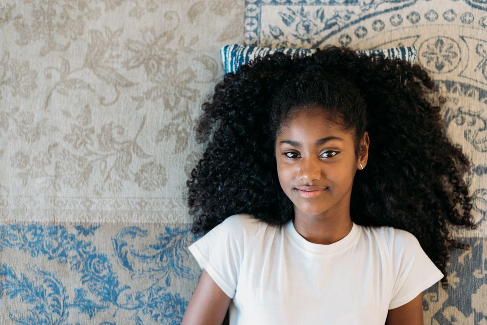 Beautiful young Black teenage girl lying down in a rug