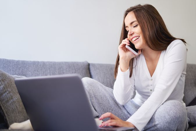 Smiling woman browsing on laptop and sitting on settee