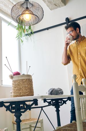 Man drinking hot tea during knitting