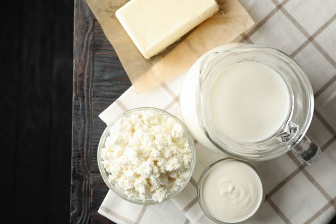 Fresh dairy products and towel on wooden background, top view