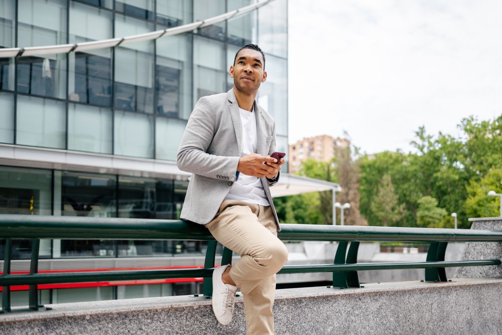 Man using smartphone leaning against wall