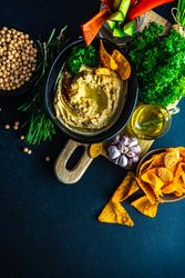Top view of traditional hummus spread with veggies and chips to dip