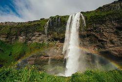 Amazing waterfall from cliff and rainbow on lawn
