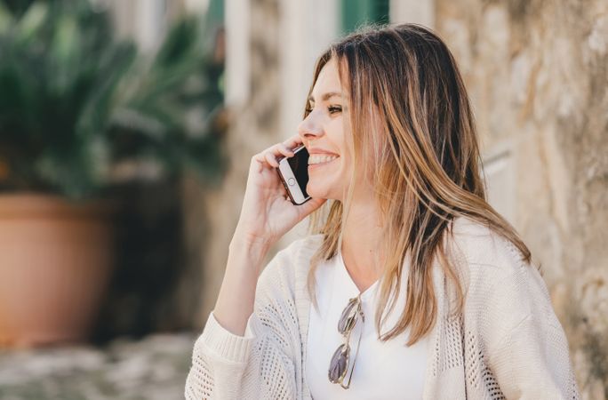 Woman with smartphone sitting on stone steps of stairs