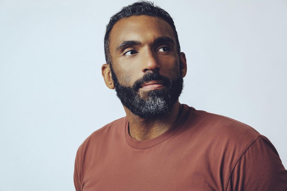 Head shot of contemplative Black male looking up in grey studio