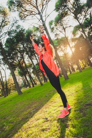 Excited sportswoman with arms raised in park
