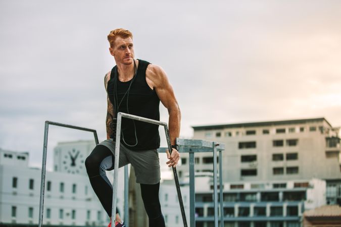 Man in fitness clothes walking up the stairs on a rooftop looking away