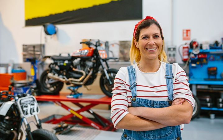 Portrait of mechanic woman standing on motorcycle factory
