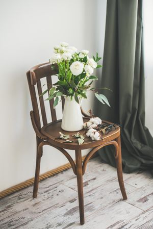 Spring buttercup flowers in enamel jug on chair