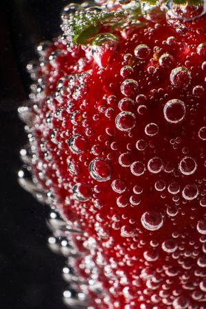 Strawberry with bubbles against dark background
