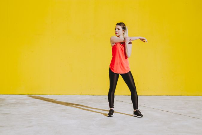 Woman stretching arms near wall