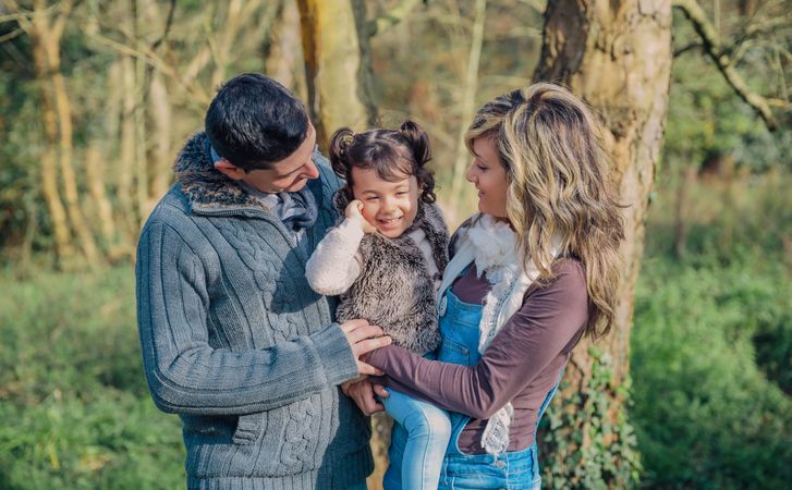 Happy parents with daughter standing in forest