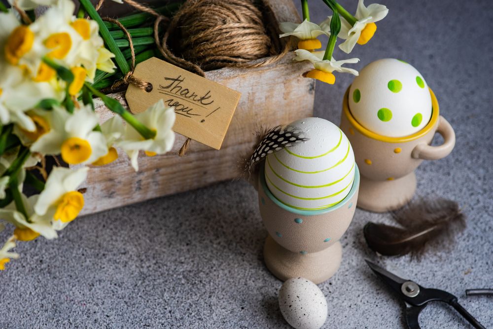 Easter floral card concept with daffodils and decorative eggs in cups