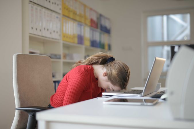 Tired woman sleeping on laptop keyboard